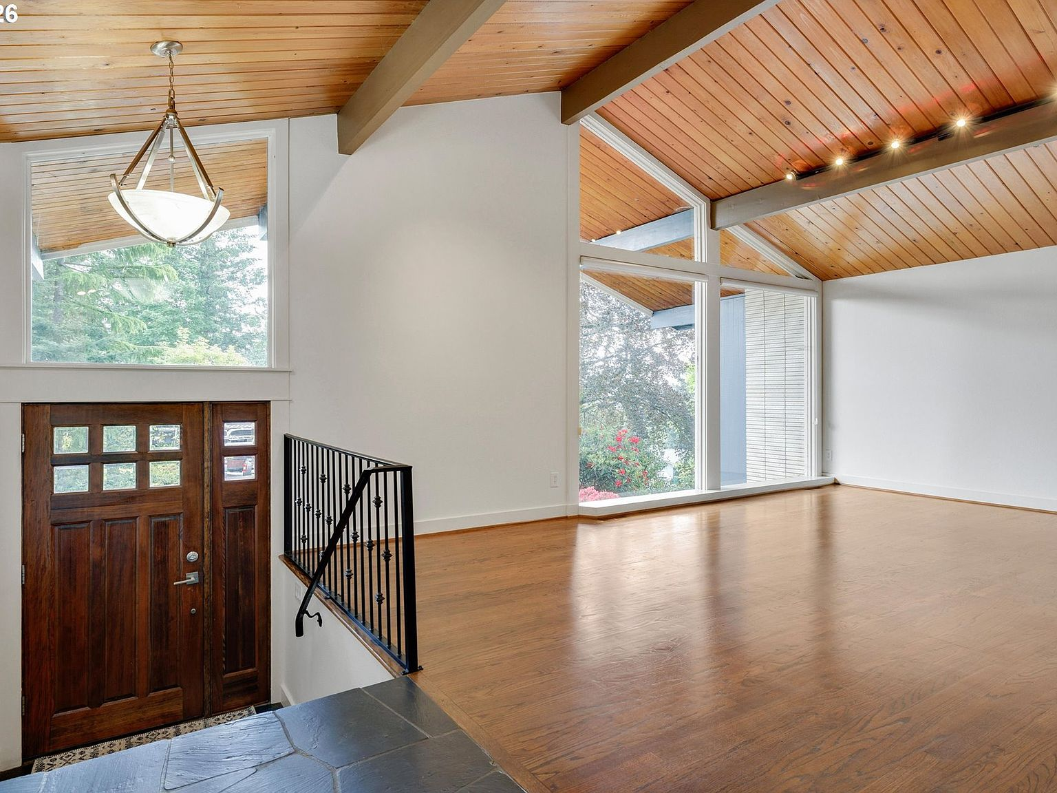 Entryway and living room with vaulted wood-plank ceiling and exposed beams