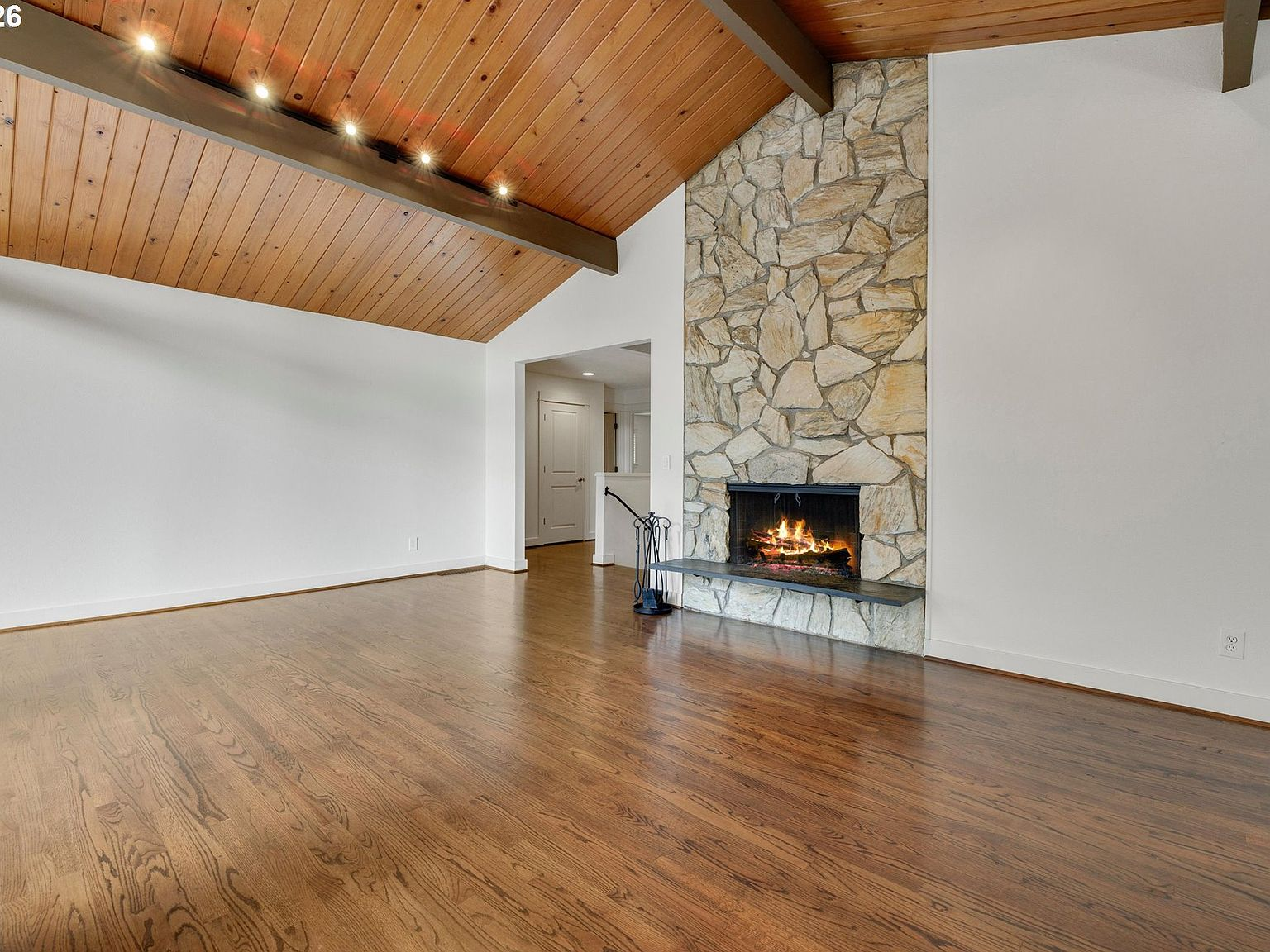 Living room with floor-to-ceiling stone fireplace and vaulted wood ceiling