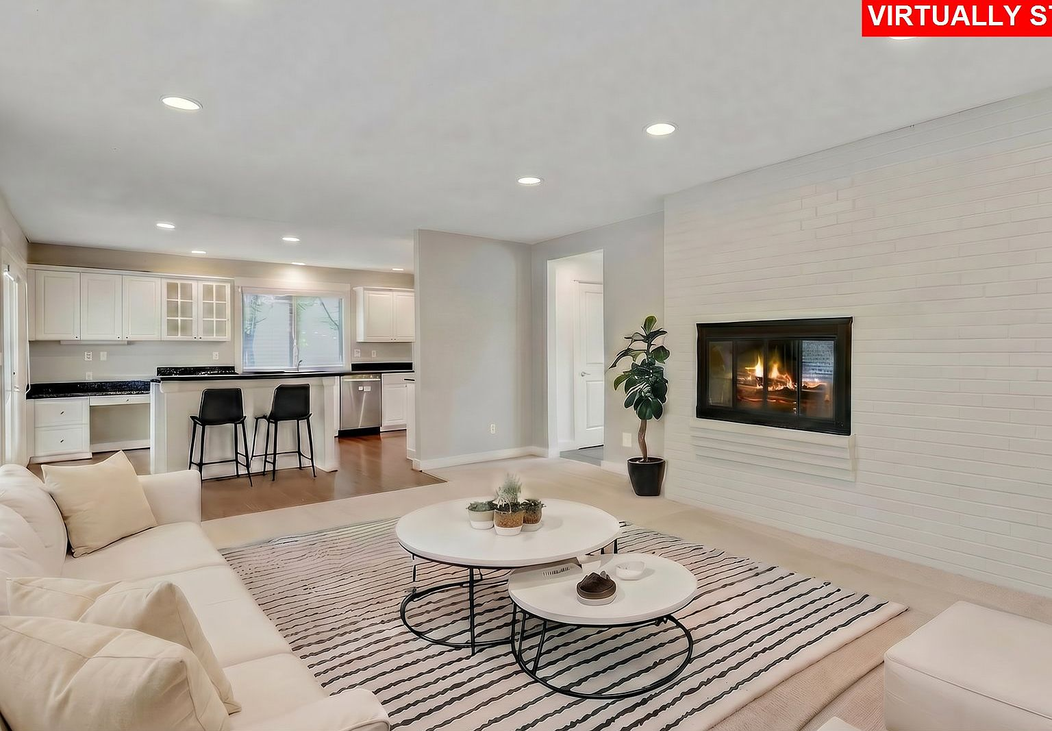 Family room with white brick fireplace overlooking kitchen