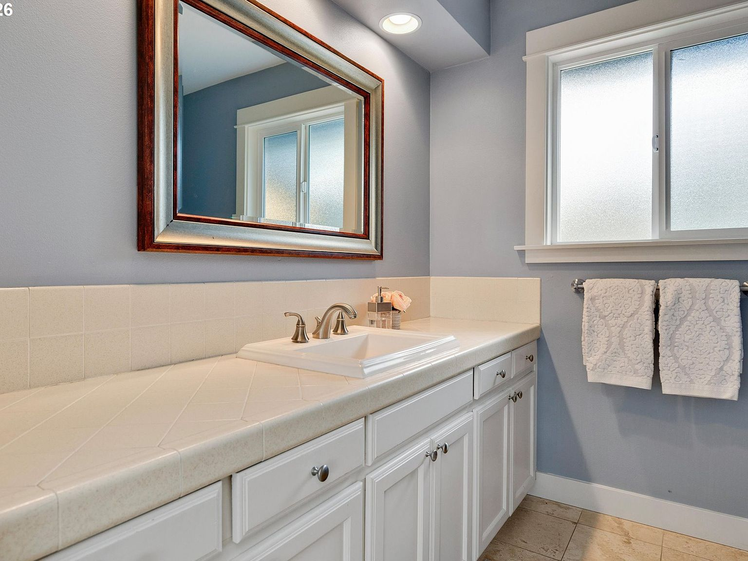 Bathroom with white tile countertop and blue walls