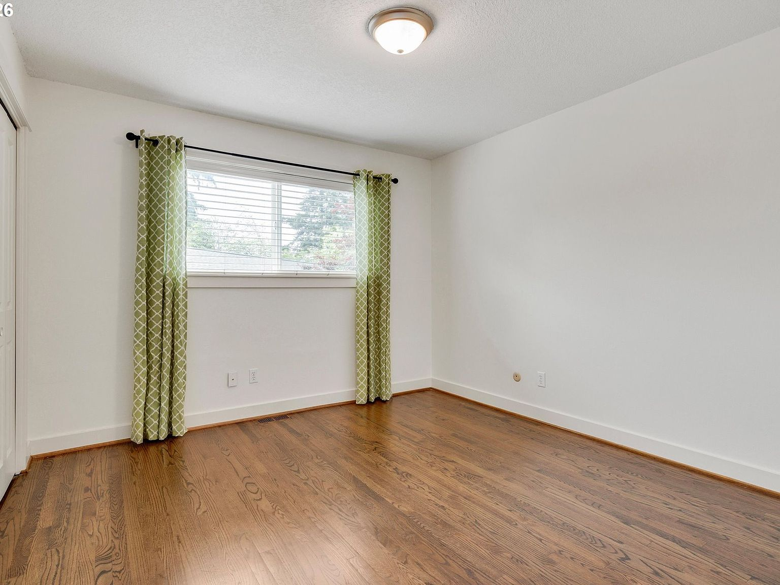 Bedroom or flex room with hardwood floors and white walls