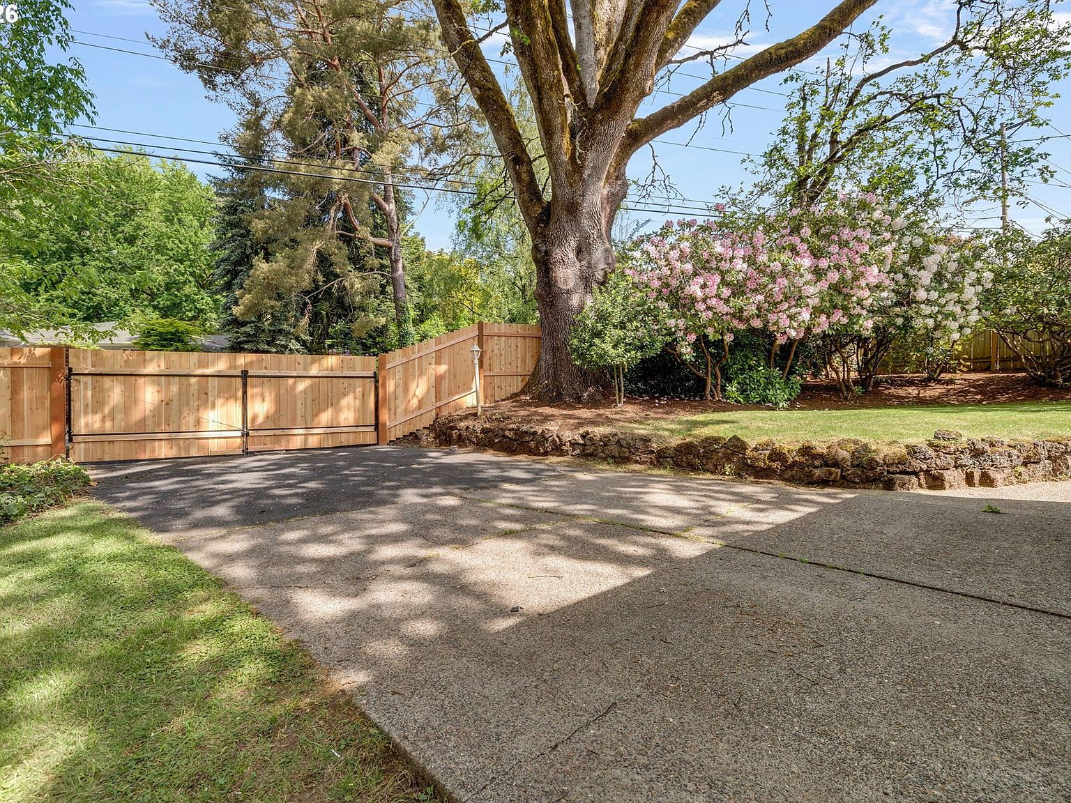 Newly installed gated driveway with wooden privacy gate and stone retaining wall