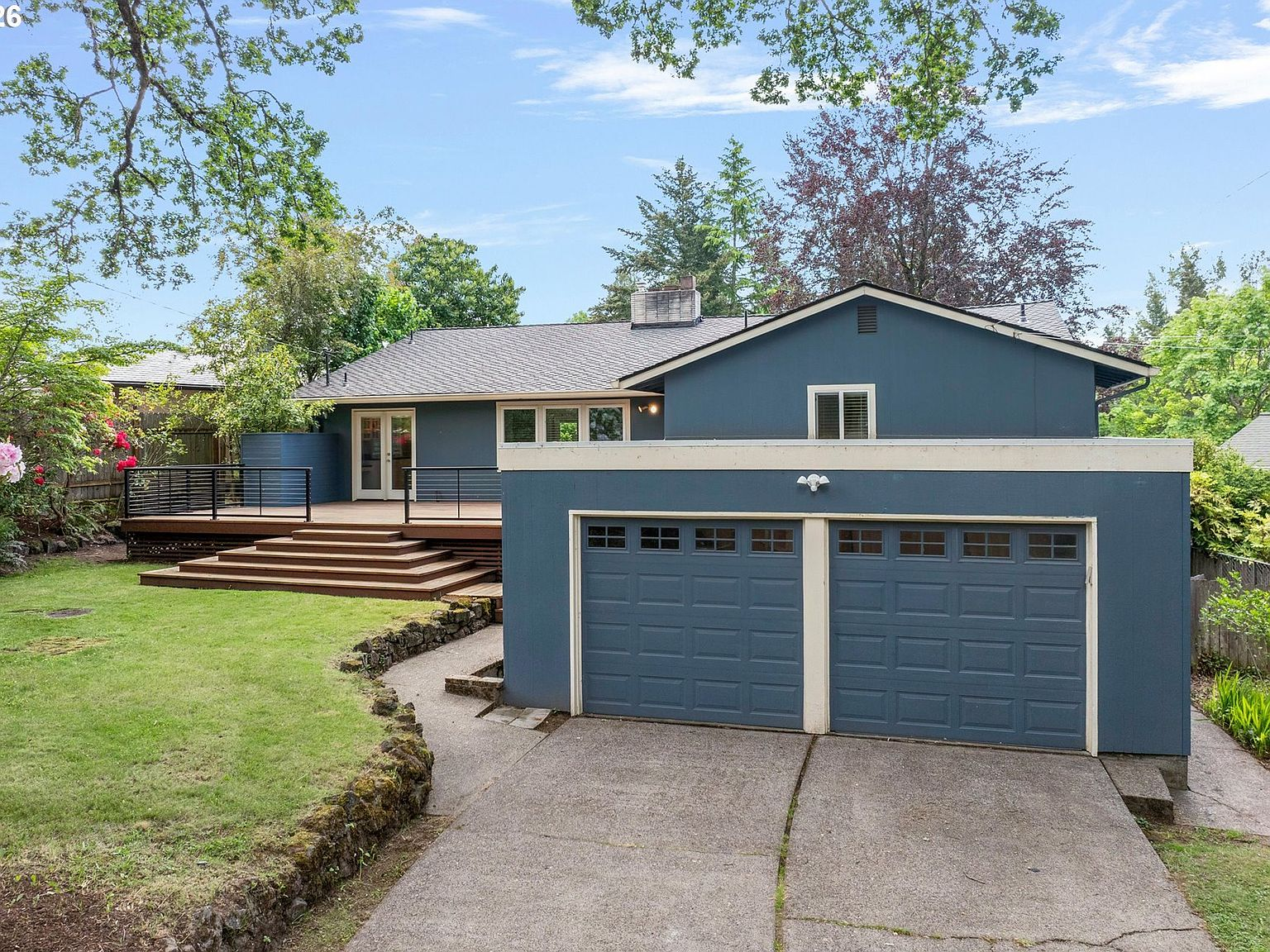 Backyard showing garage, driveway, and entertainment deck