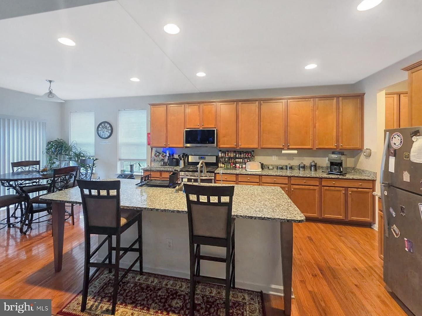 The open concept kitchen featuring warm wood cabinetry, granite island, and transition into the dining area