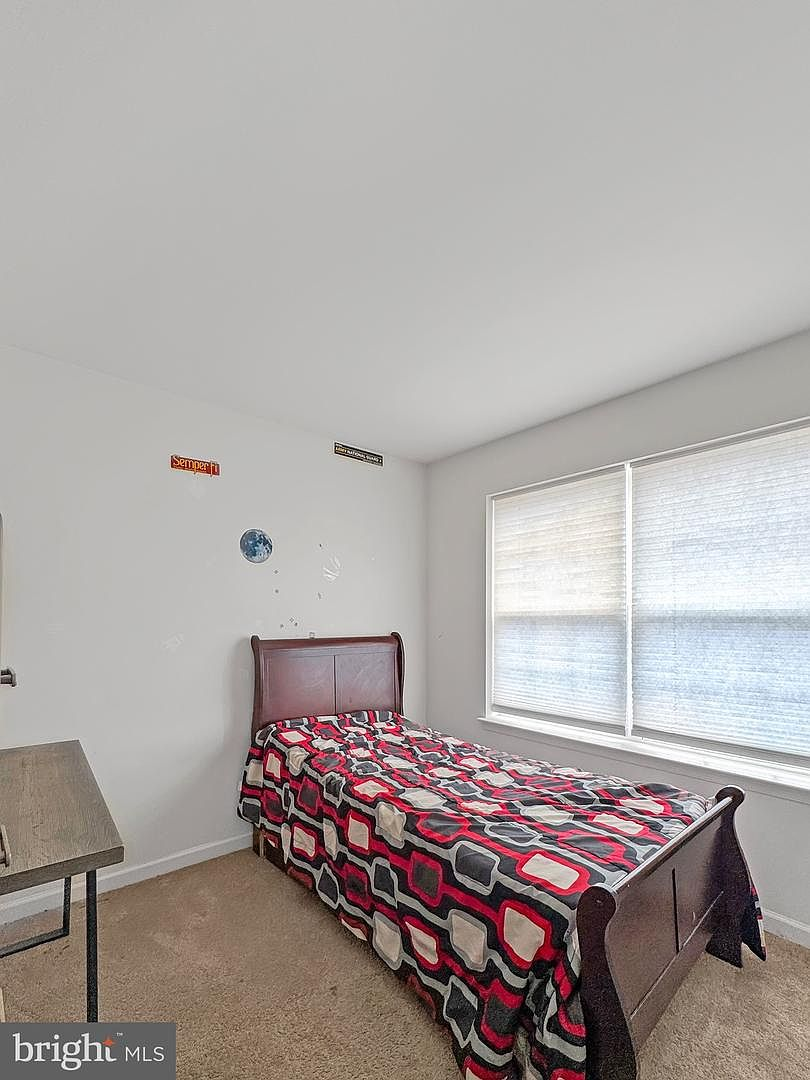 Upper-level secondary bedroom with beige carpeting, neutral painted walls, and double window