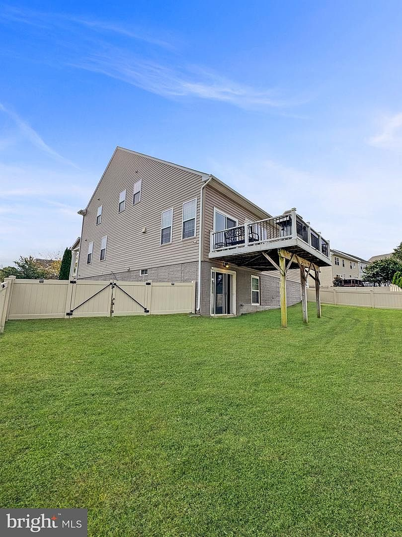 The spacious grassy backyard with completed vinyl privacy fencing and the rear elevation of the property