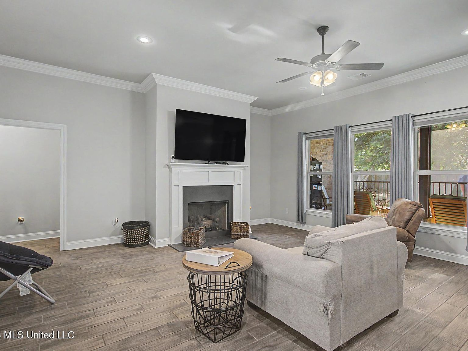 Comfortable living room anchored by an ornate gas fireplace with a neutral wood-tile hearth