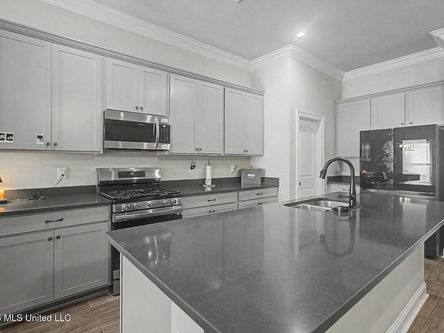 An airy shaker-style kitchen featuring a grand quartz work island and stainless steel gas range