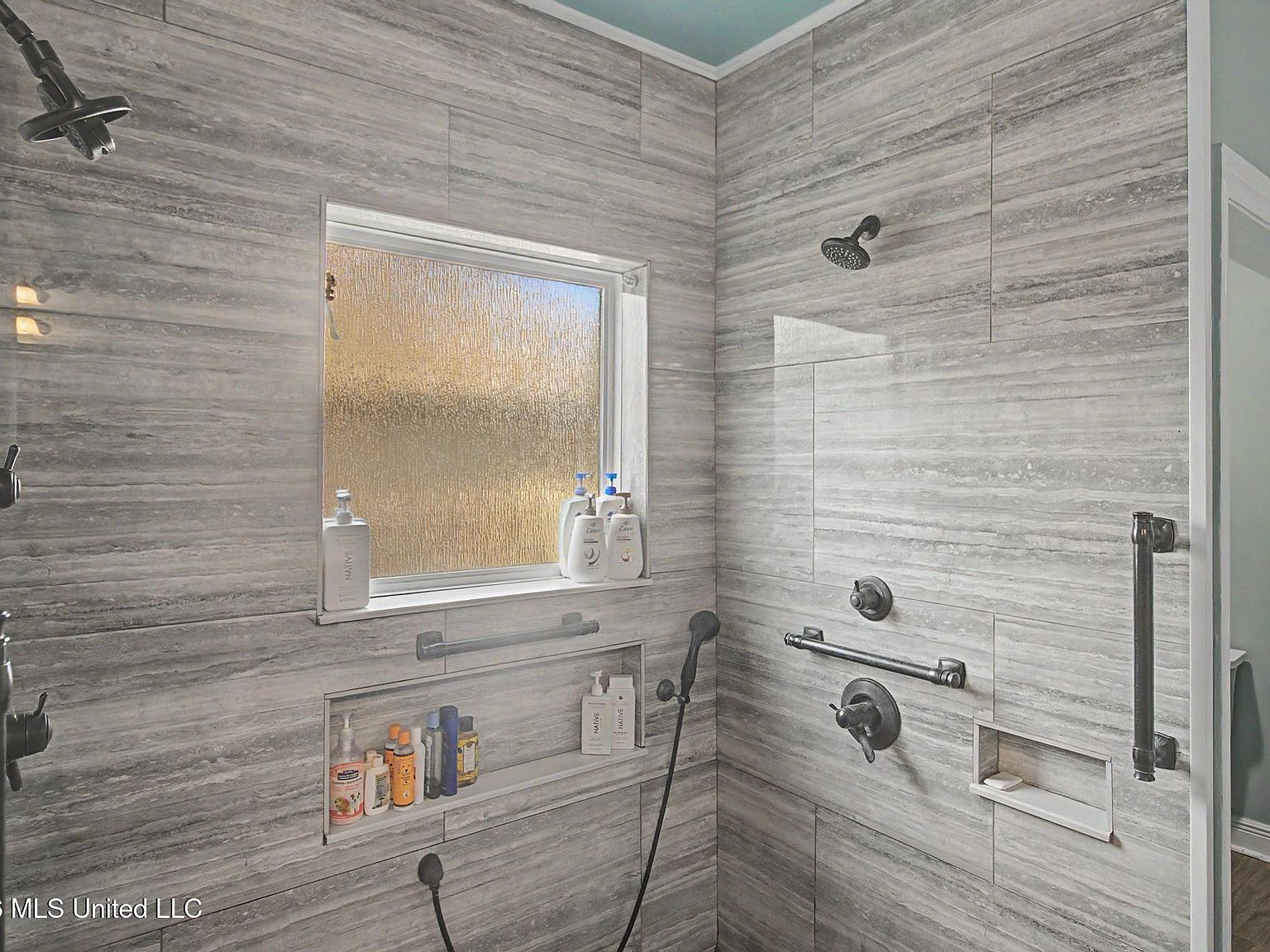 Sleek dark bronze plumbing fixtures in a spacious roll-in tiled shower