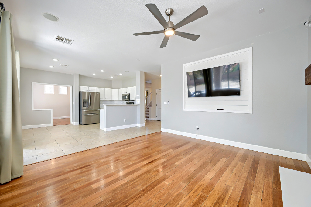 Open-concept view from the main floor hardwood living area looking straight back toward light kitchen floor tiles