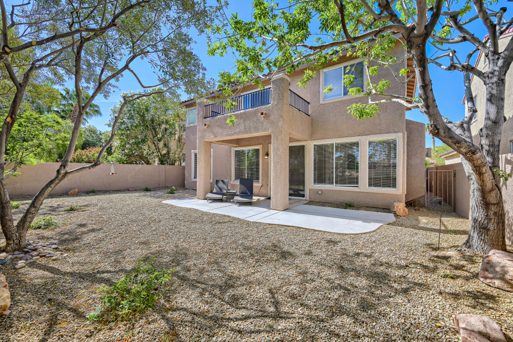 Enclosed southwest-style back patio with gravel yard and shade trees