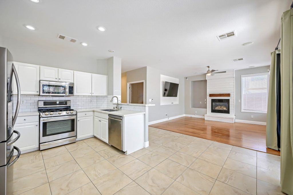 Interior open-concept kitchen looking into the adjacent living room showcasing beautiful wood floors and white cabinetry