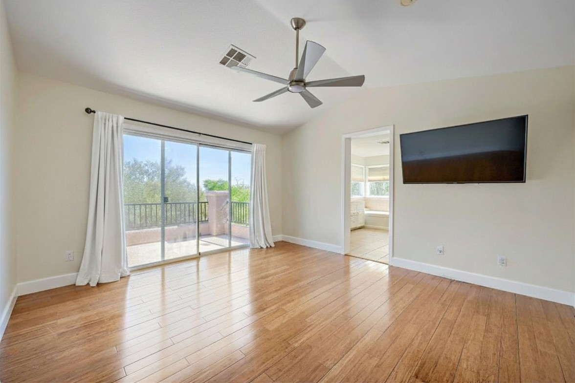 Bright master bedroom suite with modern bamboo floors and balcony sliders
