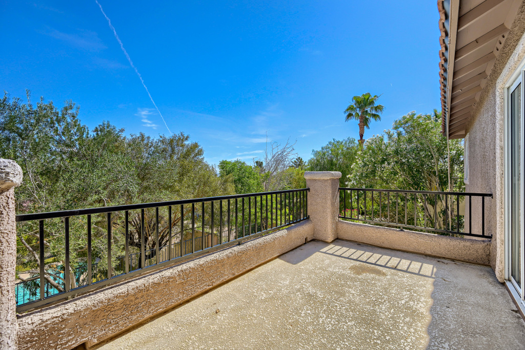 Exterior shot of the second-story balcony with stucco walls and black metal railings