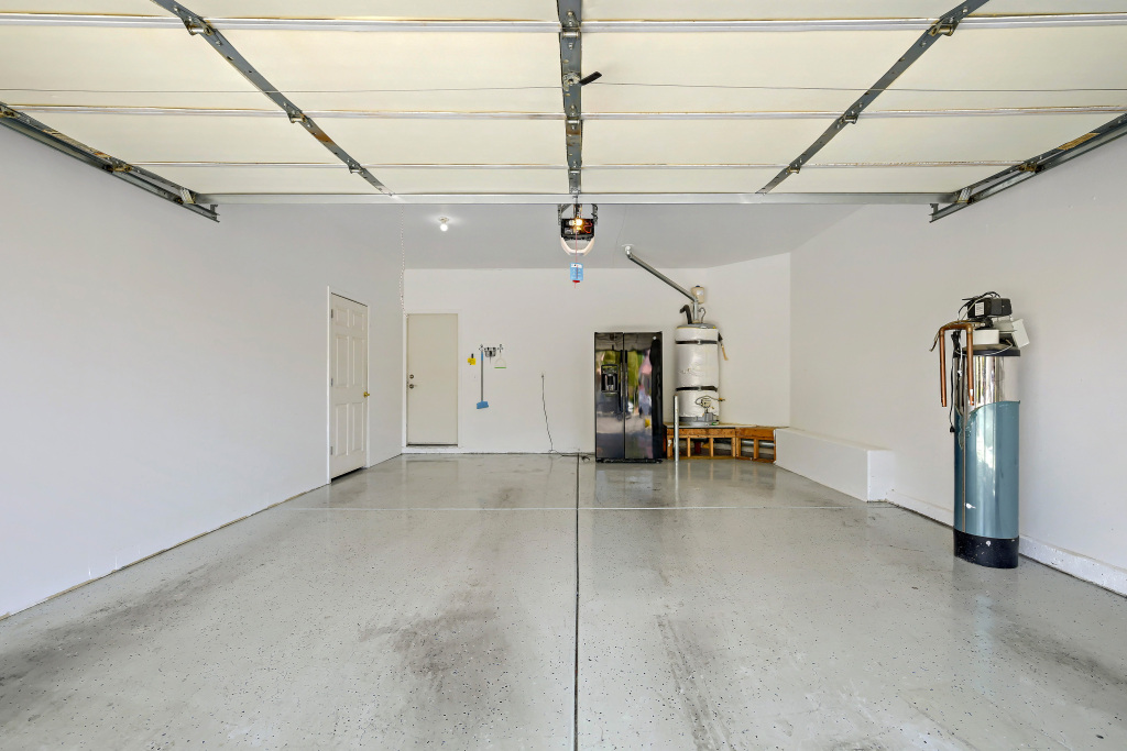 Two-car garage interior showing white painted drywall and a clean grey floor finish