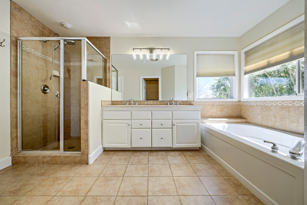 En-suite bath displaying dual layout vanity and comfortable soaking tub