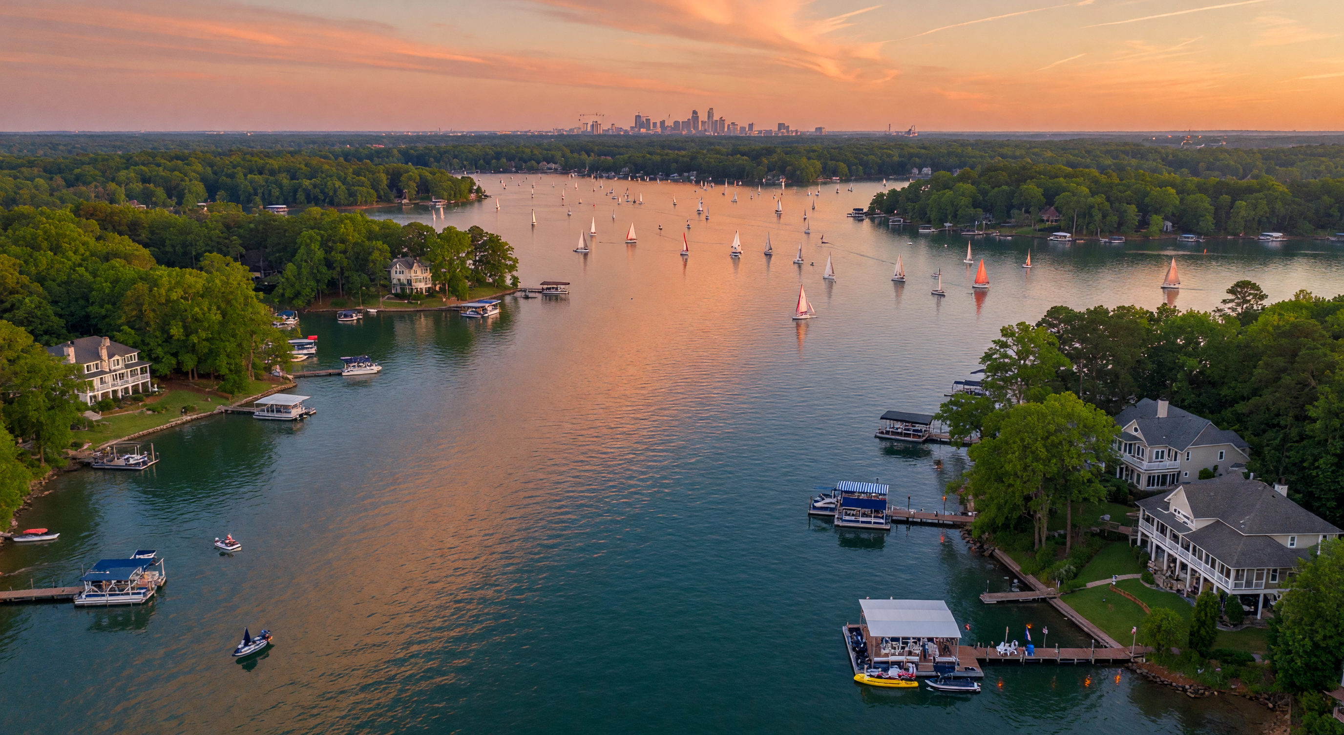 Aerial view of Lake Norman with waterfront homes and sailboats at golden hour