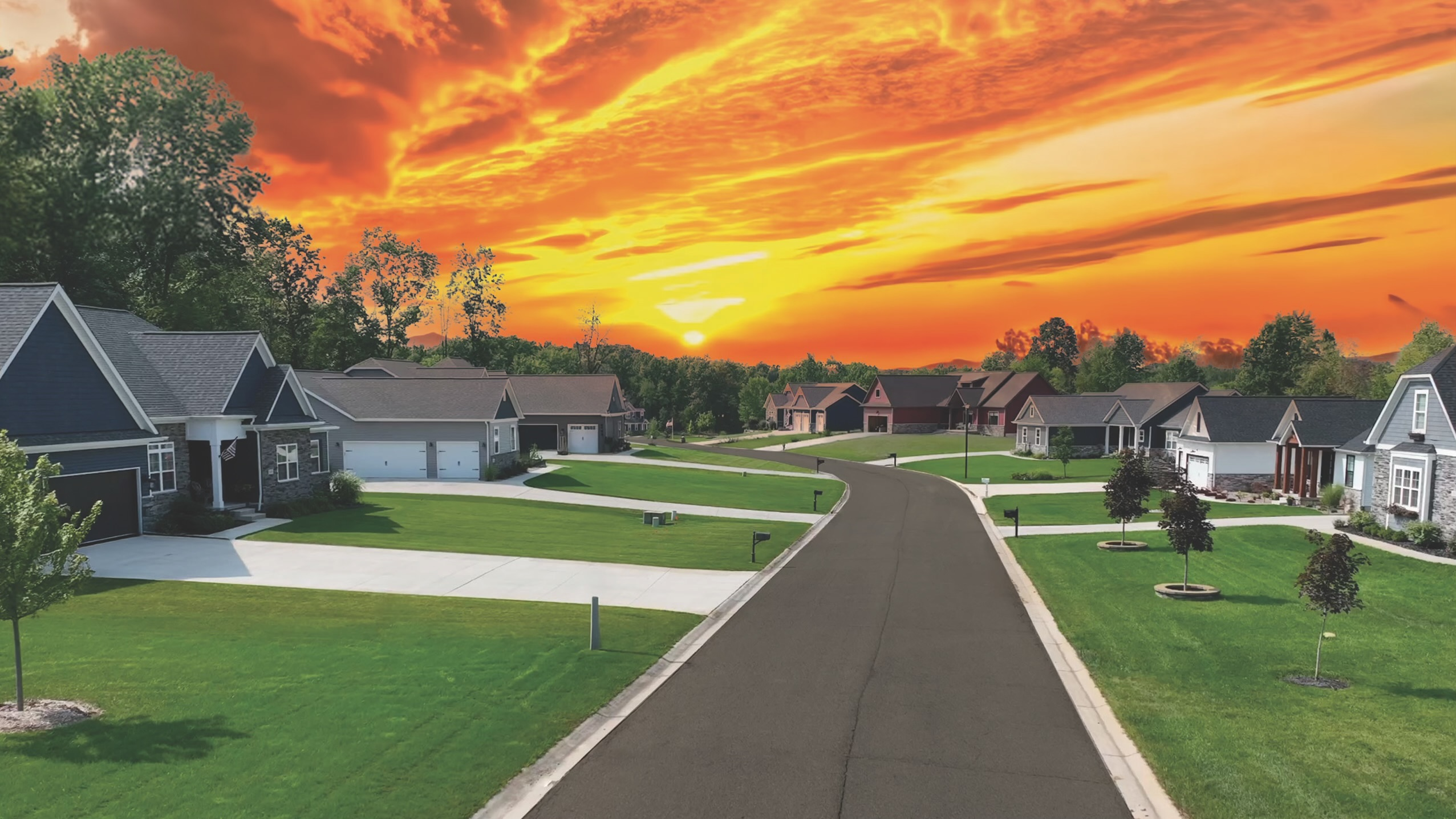 Suburban neighborhood street under a vibrant orange sunset