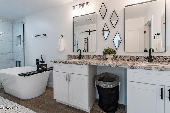 Luxurious primary bathroom en-suite with double vanities, gorgeous granite countertops, and deep freestanding soaking tub