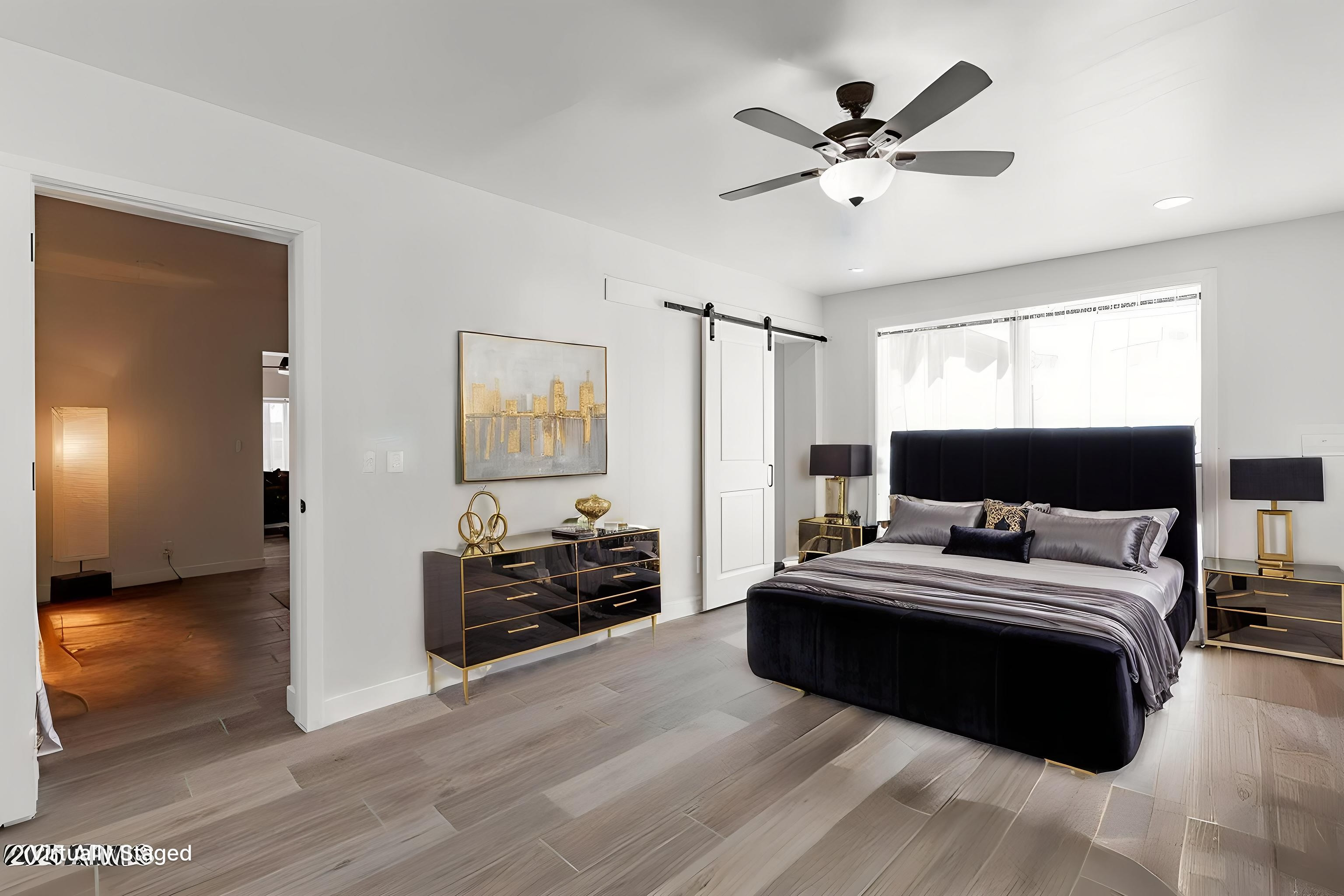 Spacious minimalist master bedroom featuring sleek tile flooring, private barn door, and large window