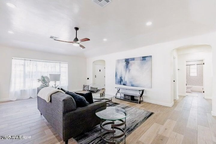 Bright and airy fully remodeled modern living room with wood-look tile flooring and arched architectural doorways