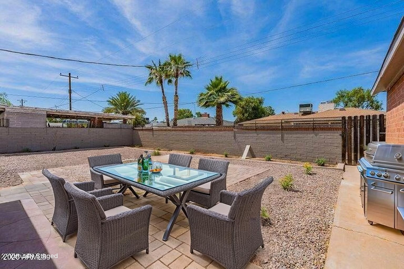 Generous private backyard with paver dining patio, gravel landscaping, and seating area under Palm trees