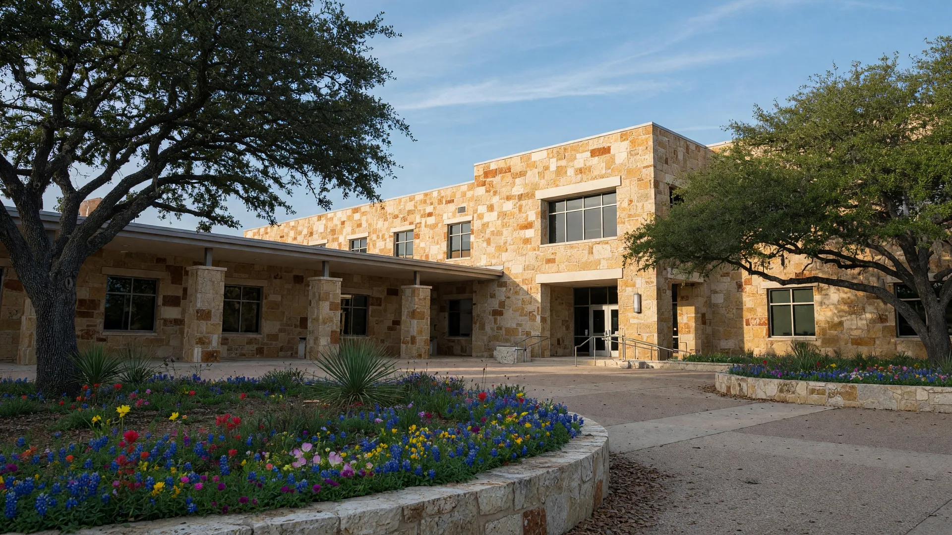 Hill Country school campus with limestone architecture and live oak trees on a spring morning