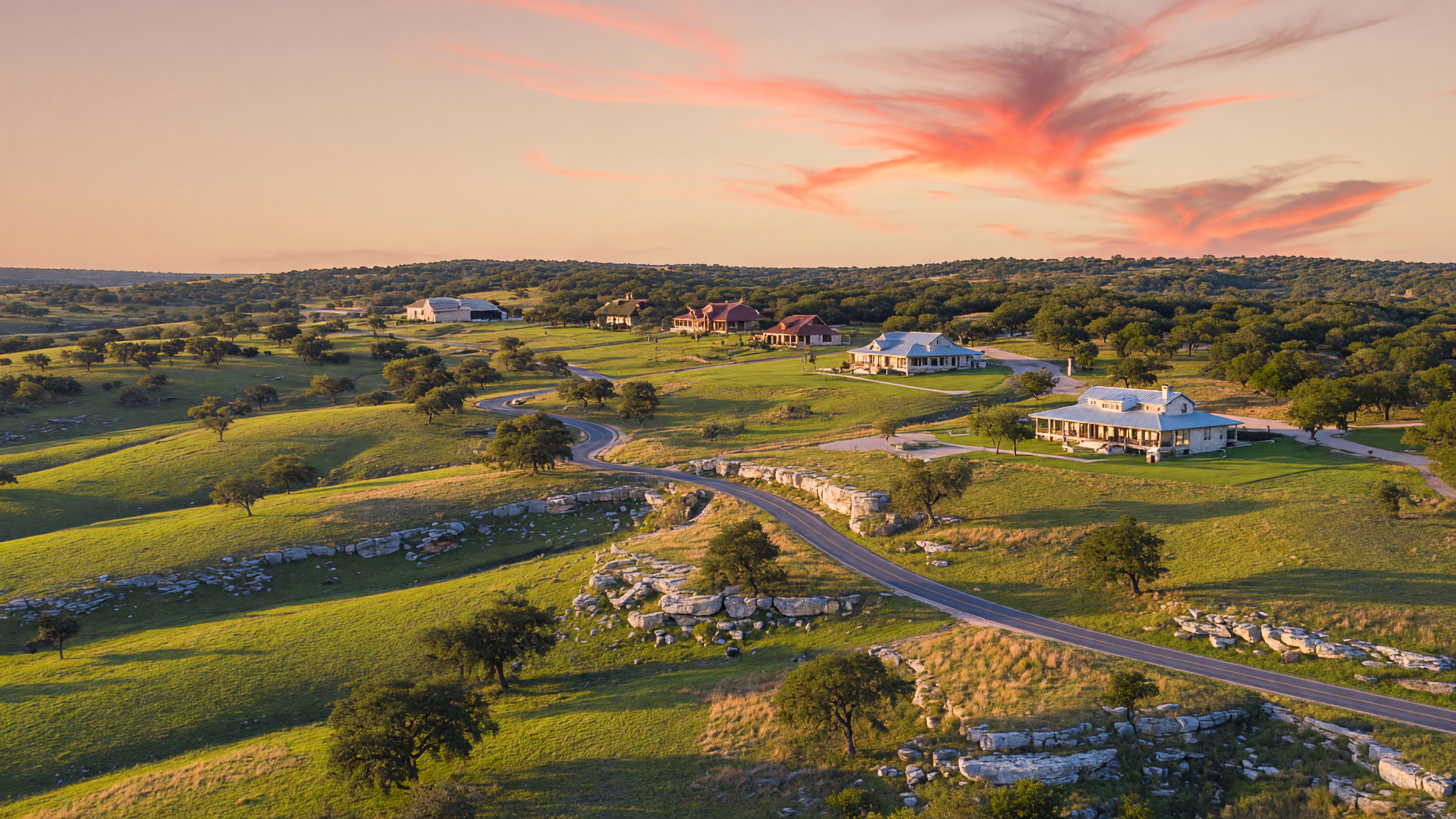 Texas Hill Country landscape with rolling hills, live oaks, and ranch homes at golden hour