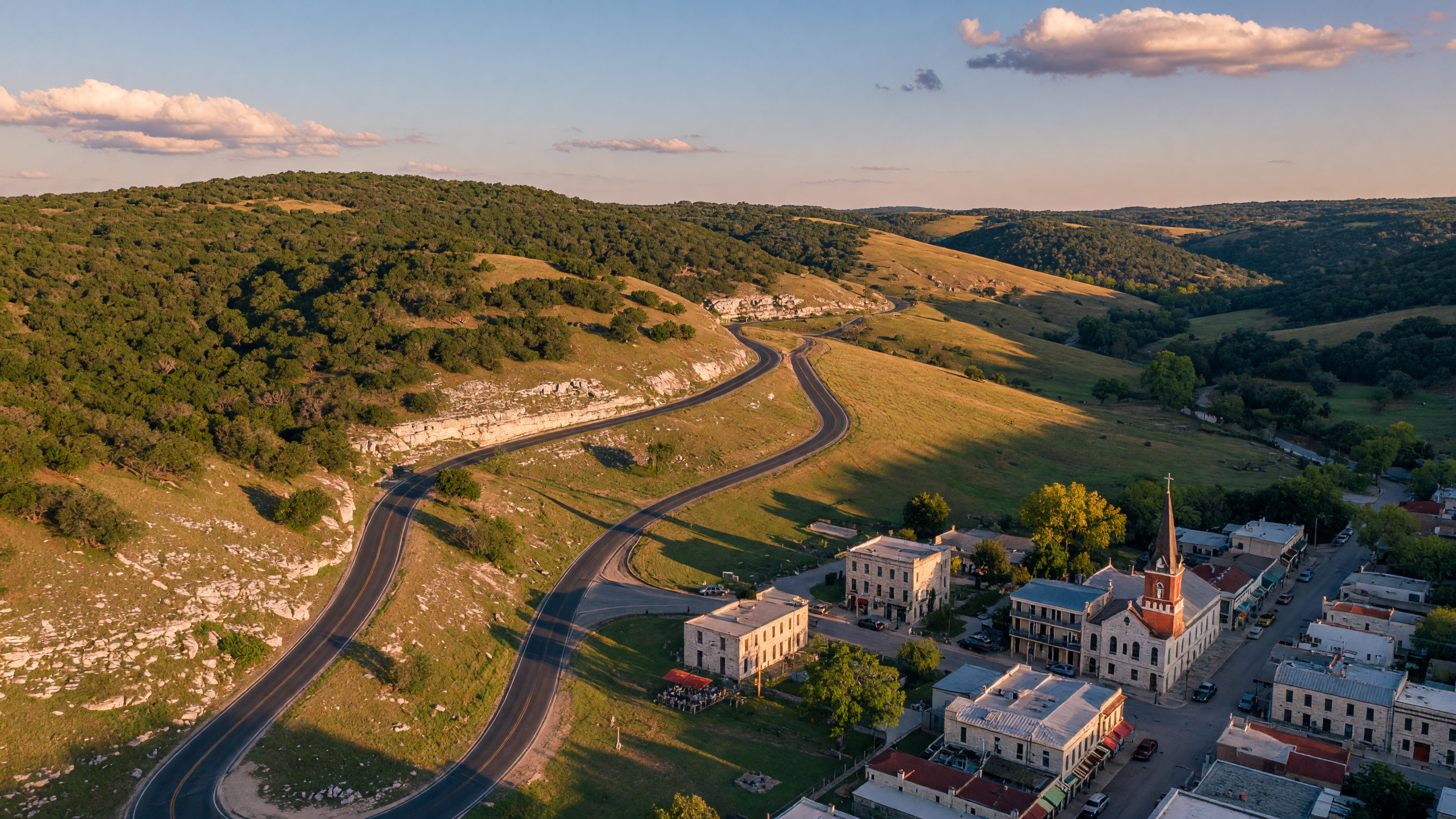 Rolling Texas Hill Country landscape with scattered oak trees and a winding road