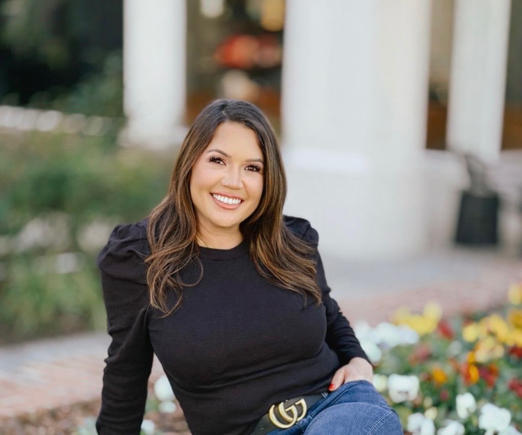 Tiffany Huntoon professional headshot in a black blouse and jeans, smiling in front of white pillars