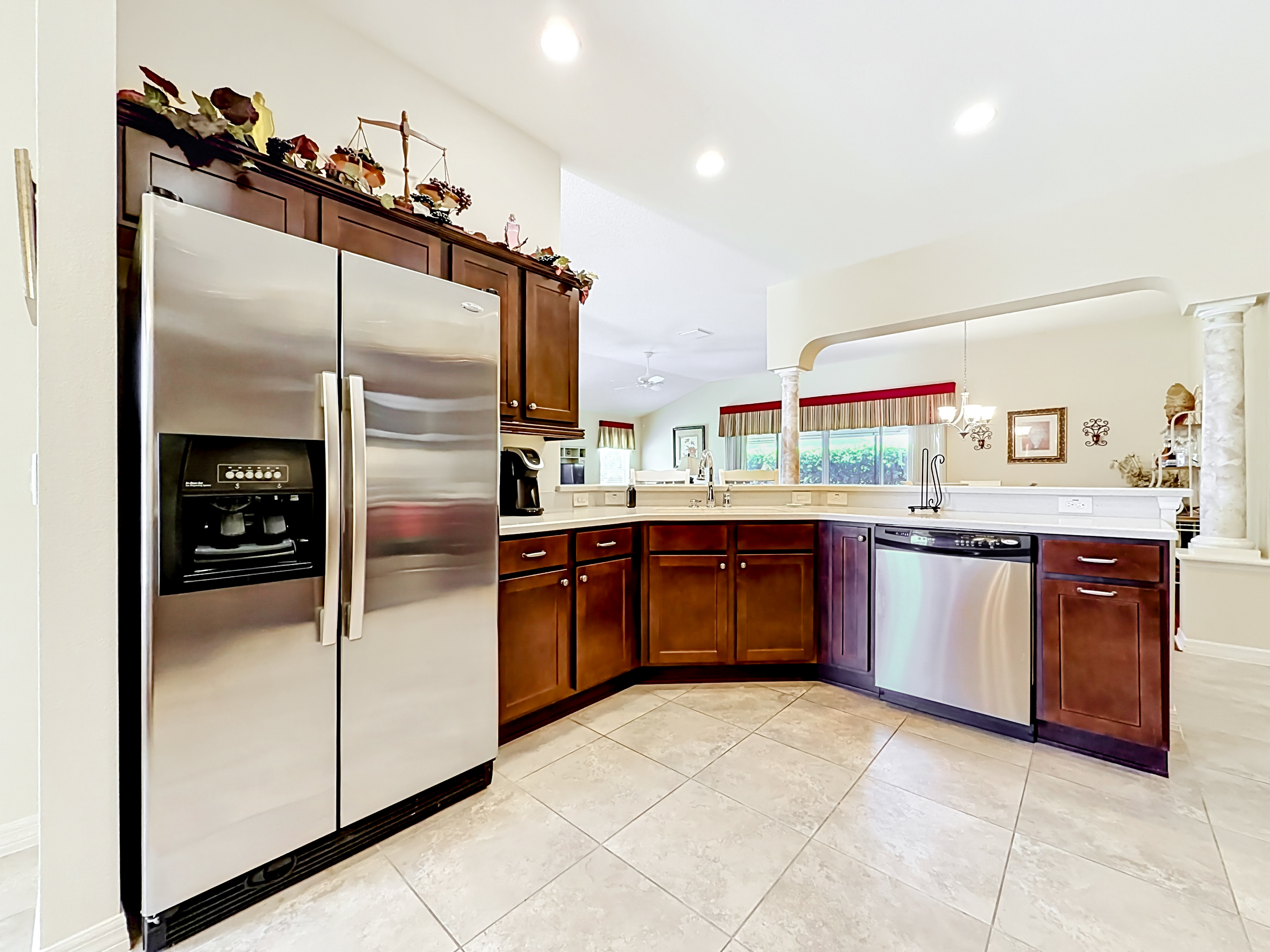 Kitchen with dark cherry wood cabinetry, stainless steel appliances, and solid-surface countertops