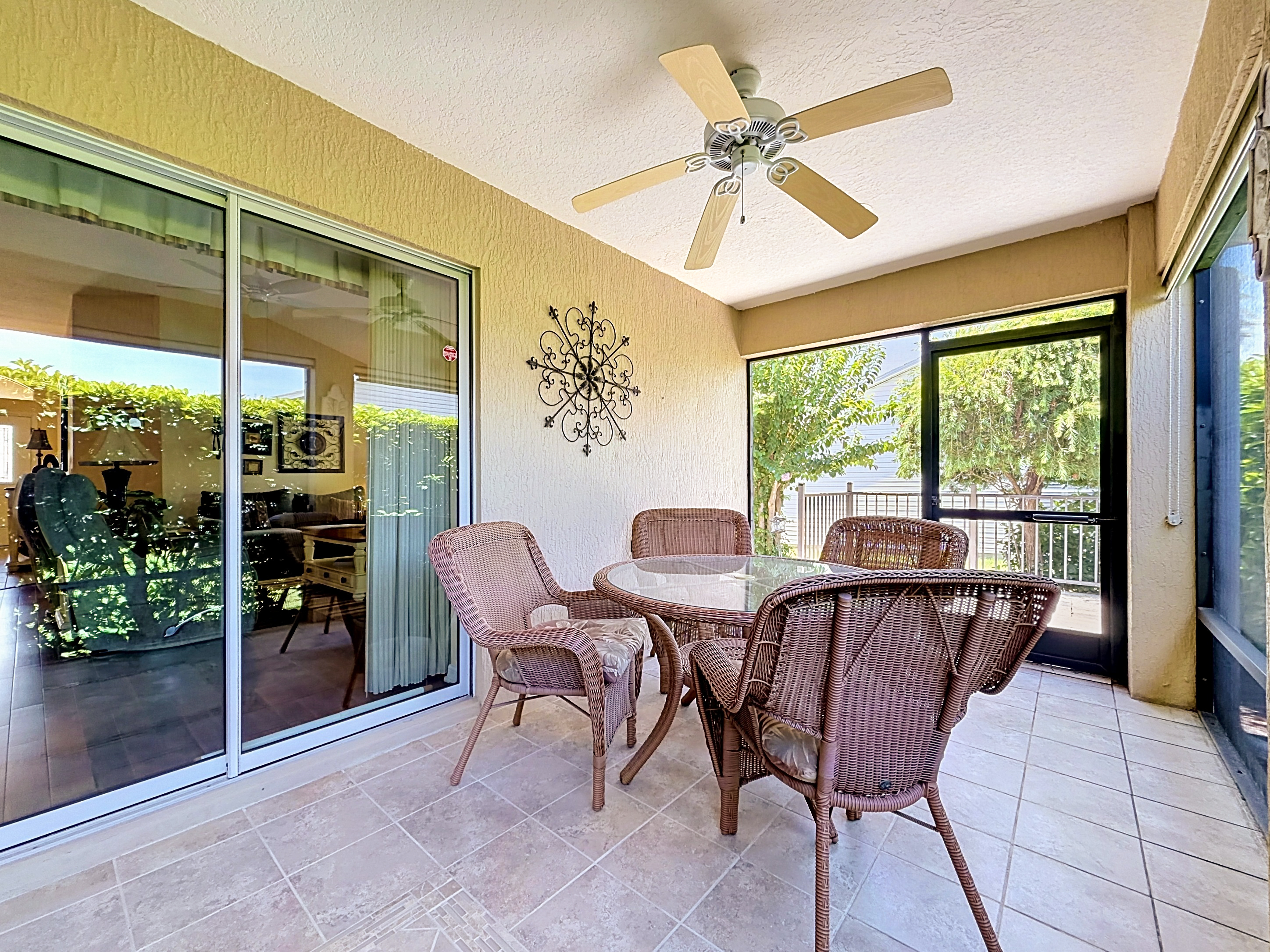 Screened lanai patio with tile flooring, ceiling fans, and wicker furniture for year-round Florida living