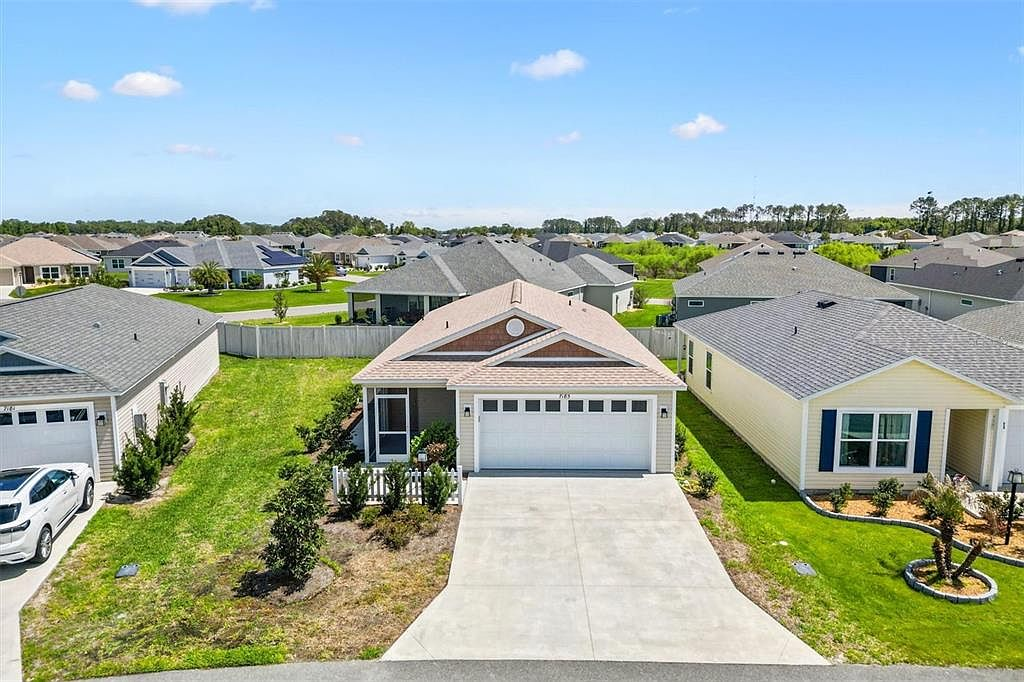 Aerial drone view of the front exterior of 7185 Fay Ct showing the driveway, garage, and surrounding Villages neighborhood