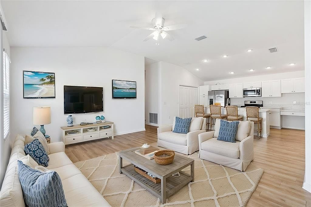 Virtual staged open-concept living area at 7185 Fay Ct showing the kitchen island, living room, and vaulted ceilings