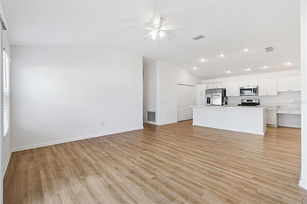 Open-concept living and kitchen area with vaulted ceilings, luxury vinyl plank flooring, and recessed lighting