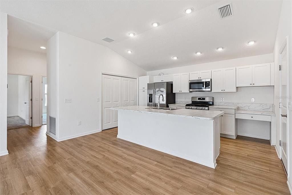 Modern kitchen with oversized island, white shaker cabinetry, marble-look countertops, and stainless steel appliances