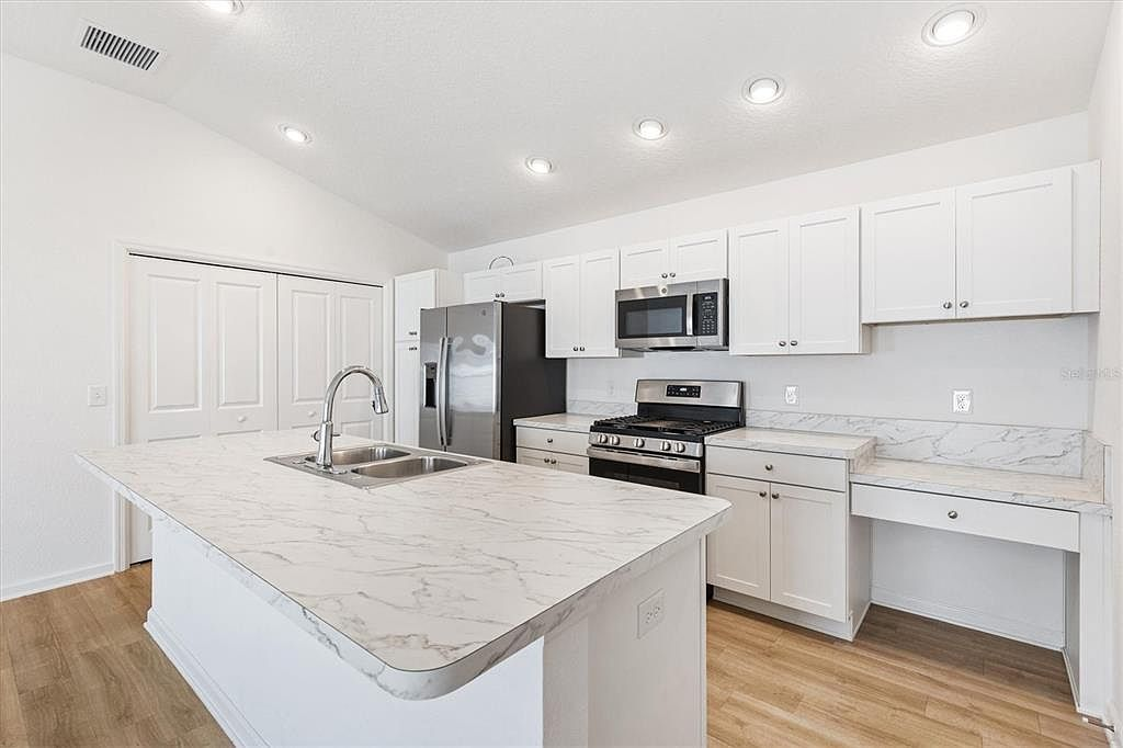 Kitchen detail showing white shaker cabinets with soft-close drawers and marbled countertops