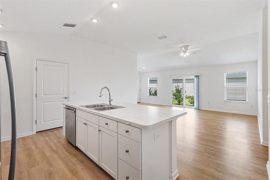 Kitchen looking toward living area and screened patio doors with natural light pouring through at 7185 Fay Ct