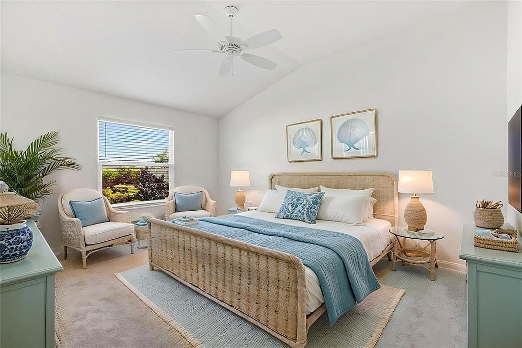 Primary bedroom virtually staged with coastal furnishings, vaulted ceilings, and ceiling fan