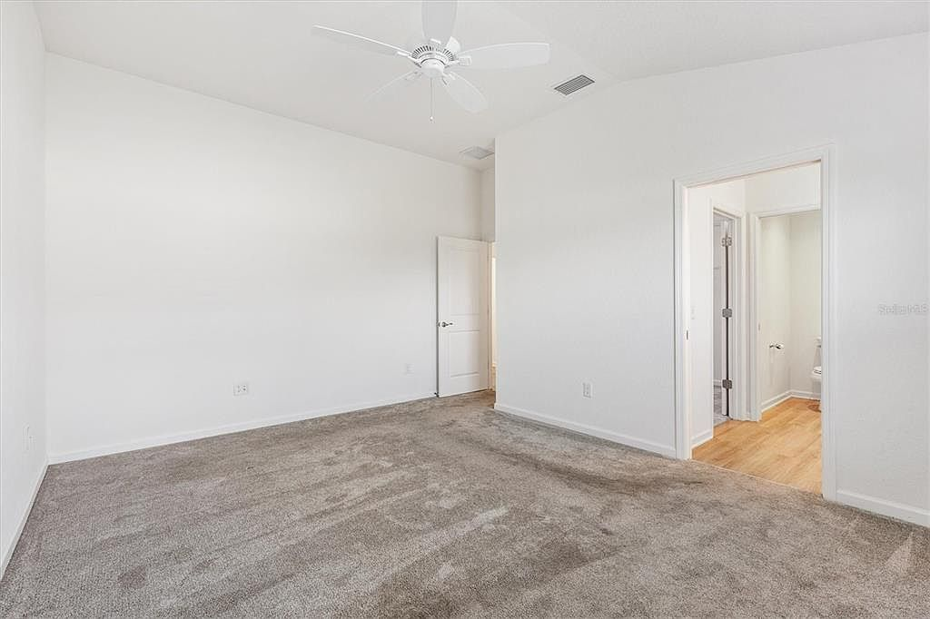Vacant primary bedroom with vaulted ceiling, ceiling fan, and carpeted flooring at 7185 Fay Ct