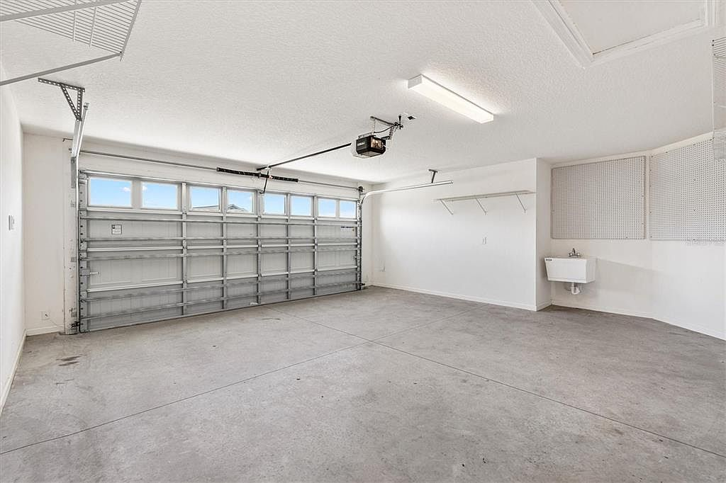 Clean, spacious two-car garage interior at 7185 Fay Ct with built-in shelving and utility sink