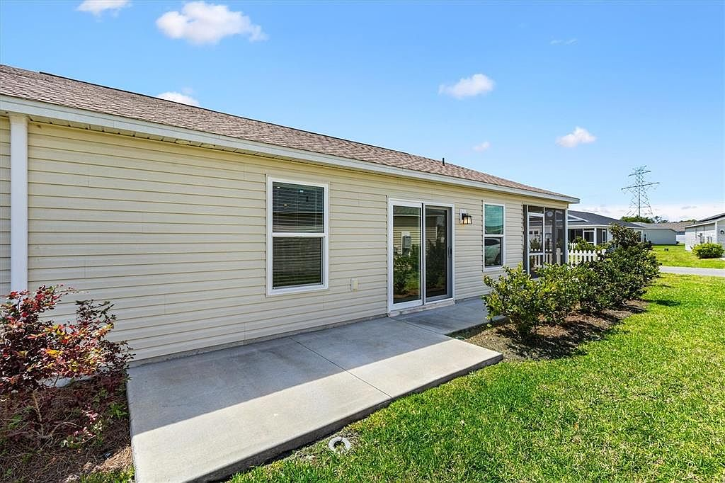 Rear exterior with concrete patio, fenced backyard, and white vinyl privacy fencing