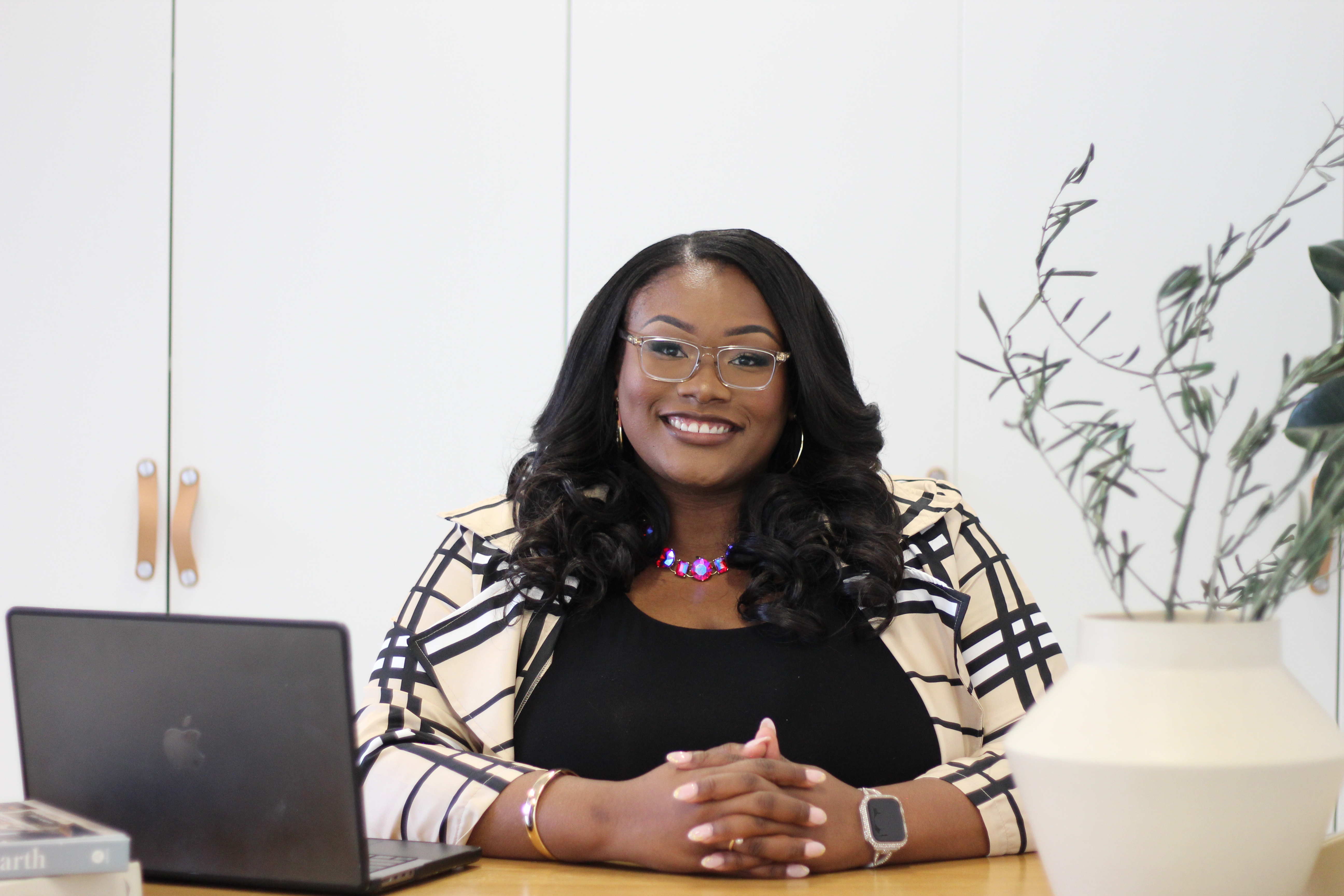 Tory Akene at a bright workspace with laptop and decorative plant