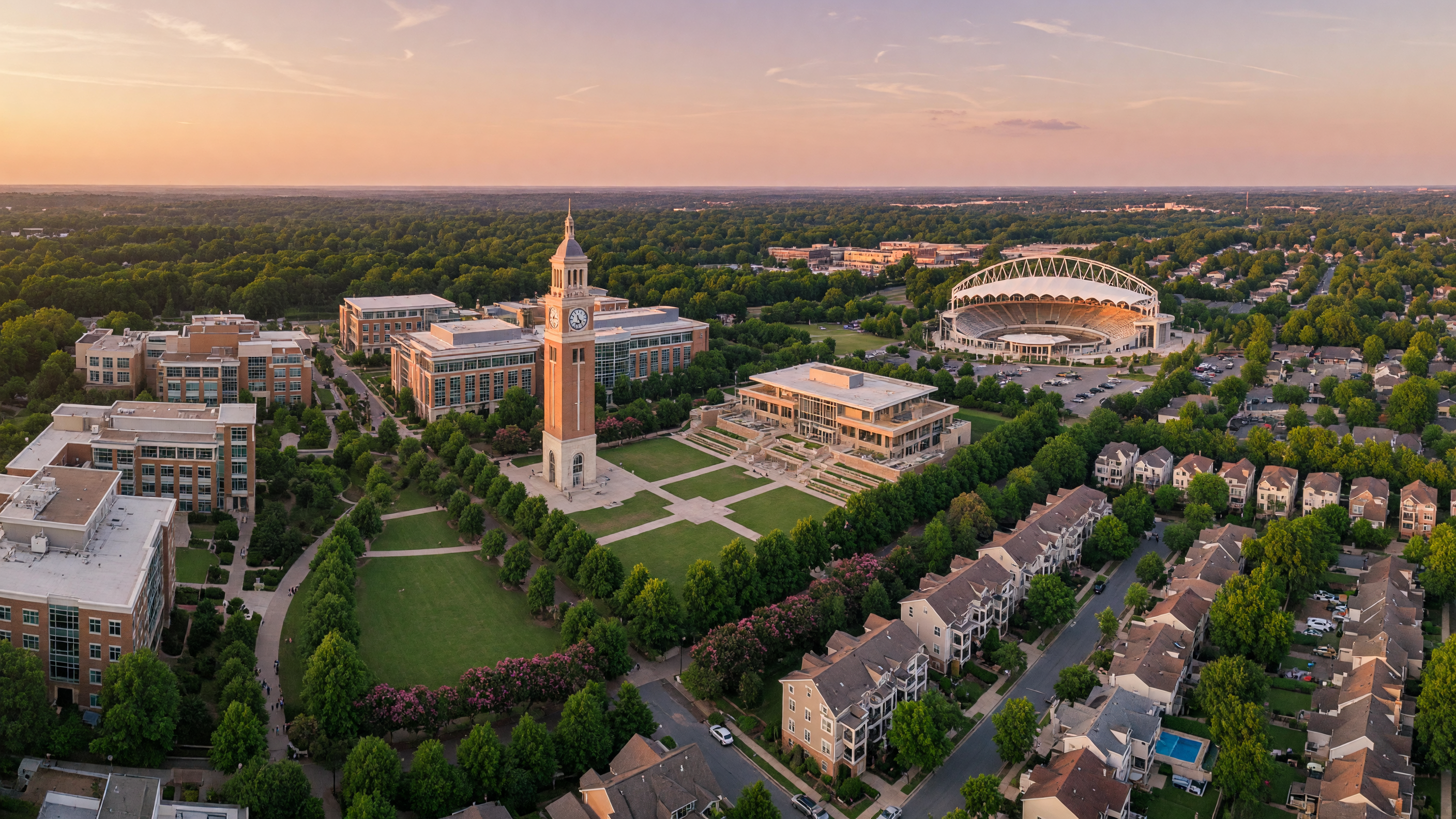 UNC Charlotte campus and University City corridor with modern buildings and tree canopy at golden hour