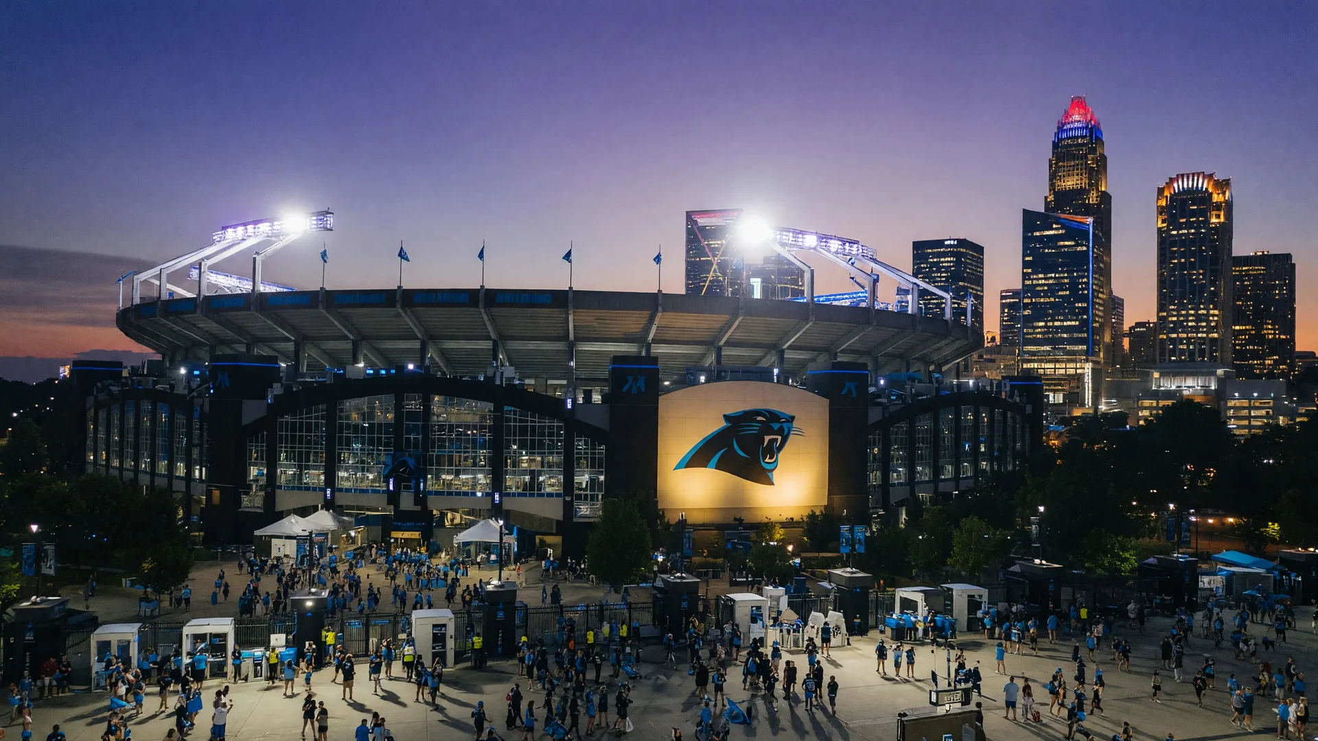 Bank of America Stadium in Charlotte NC on a summer evening with stadium lights glowing against twilight sky