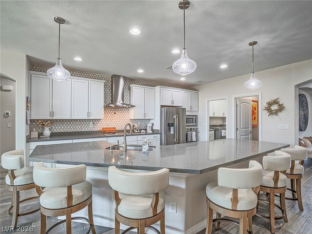 Kitchen with white cabinetry, quartz counters, and pendant lights