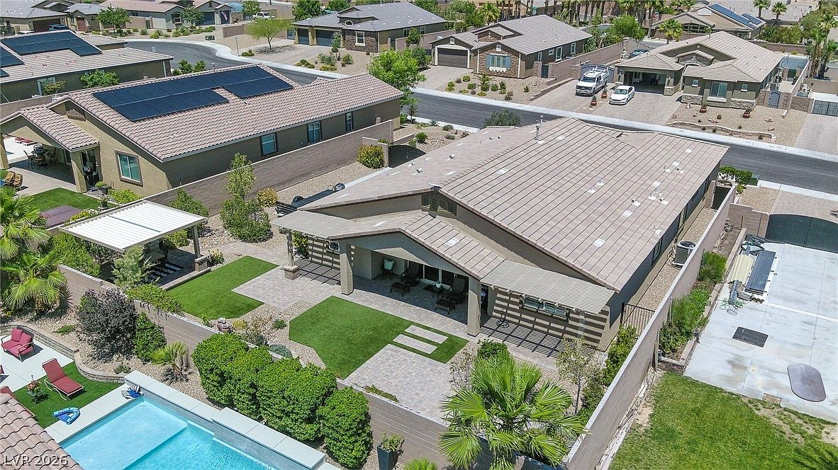 Aerial drone shot of backyard with pool, pavilion, and solar panels