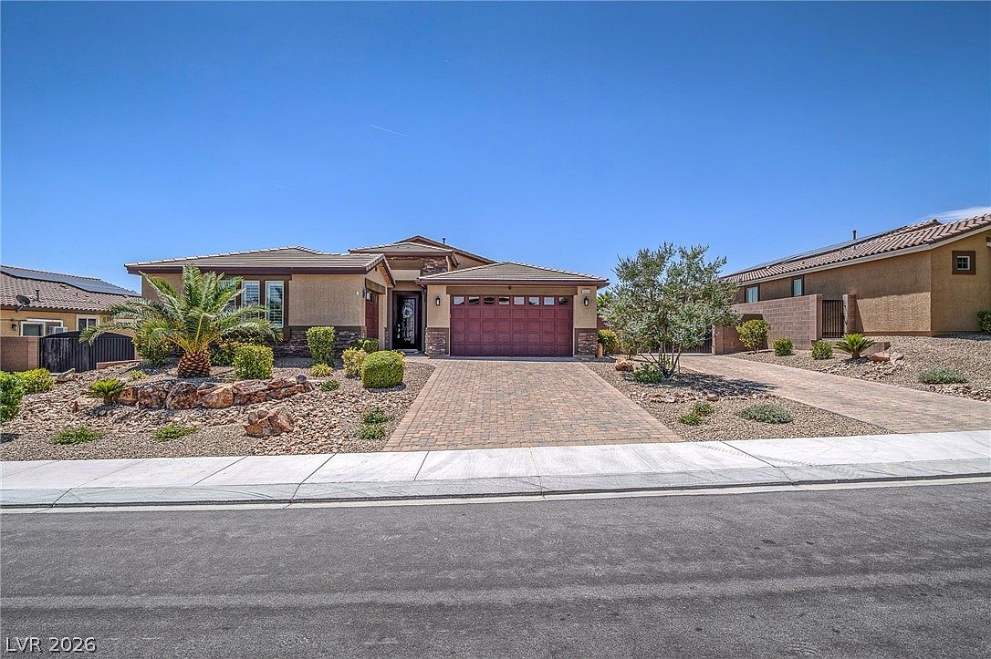 Front facade with paved driveway, multi-car garage, and desert landscaping