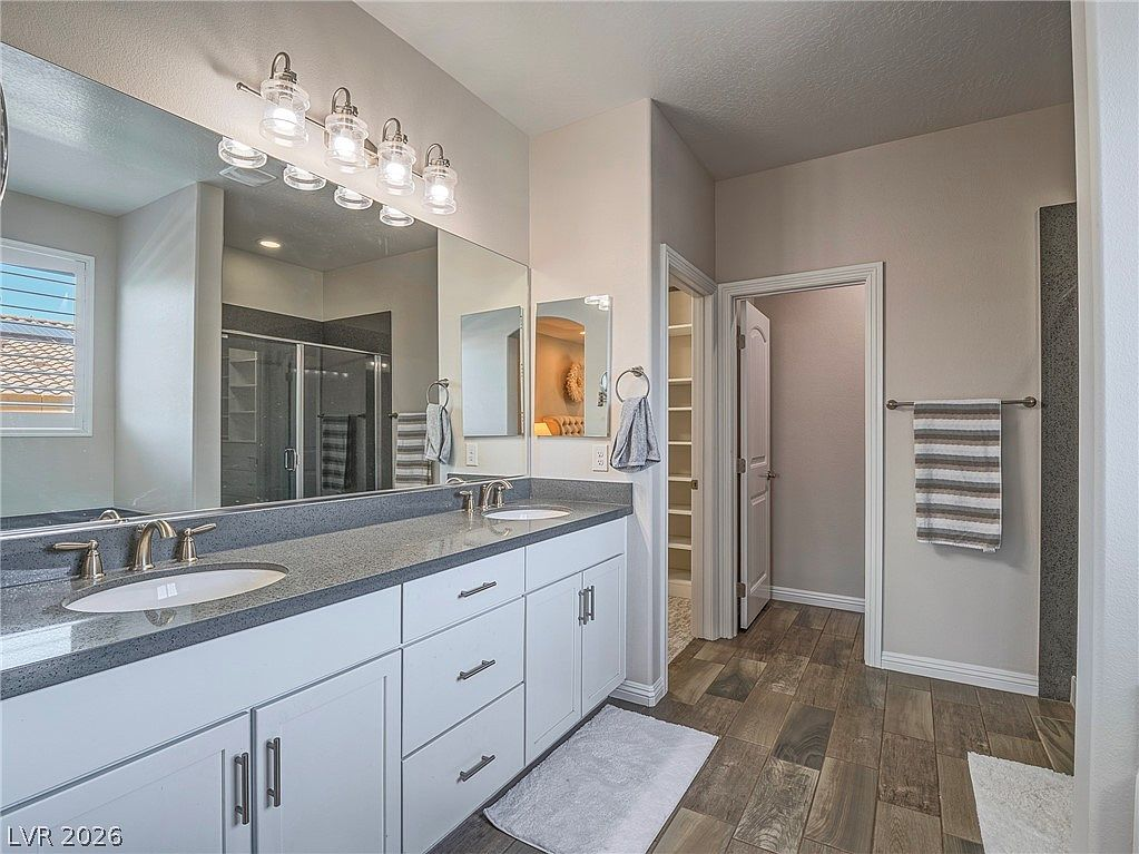 Primary bathroom with white shaker cabinets and dark countertops