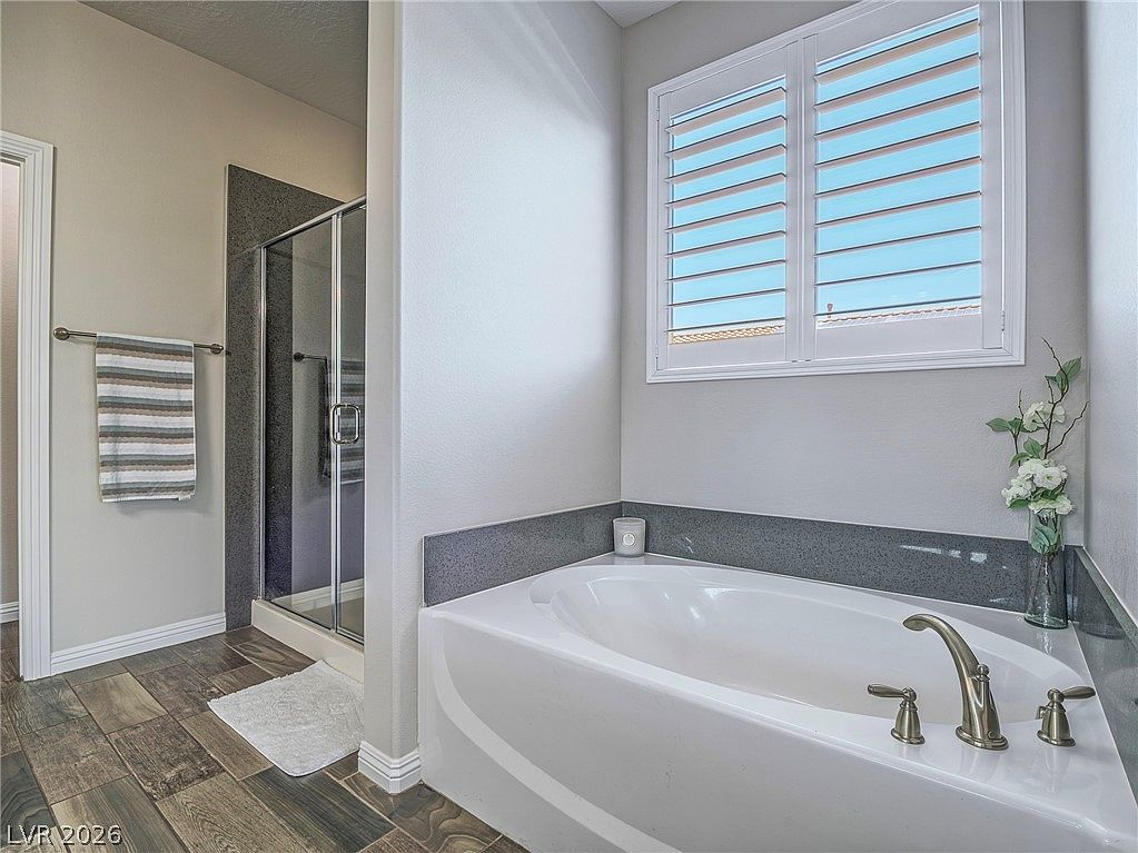 Primary bathroom with white soaking tub and dark stone surround
